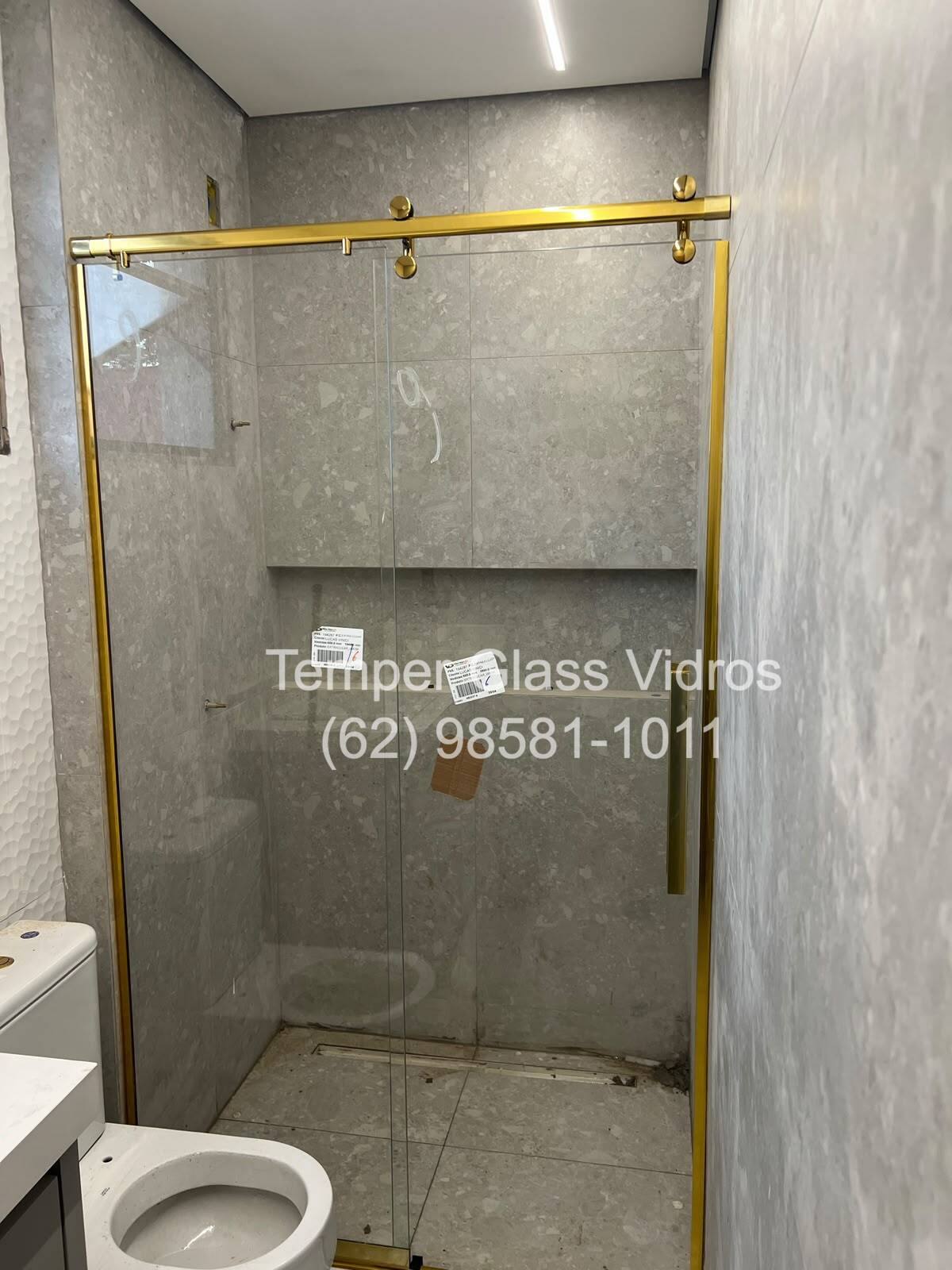 Box de vidro com moldura dourada em banheiro moderno